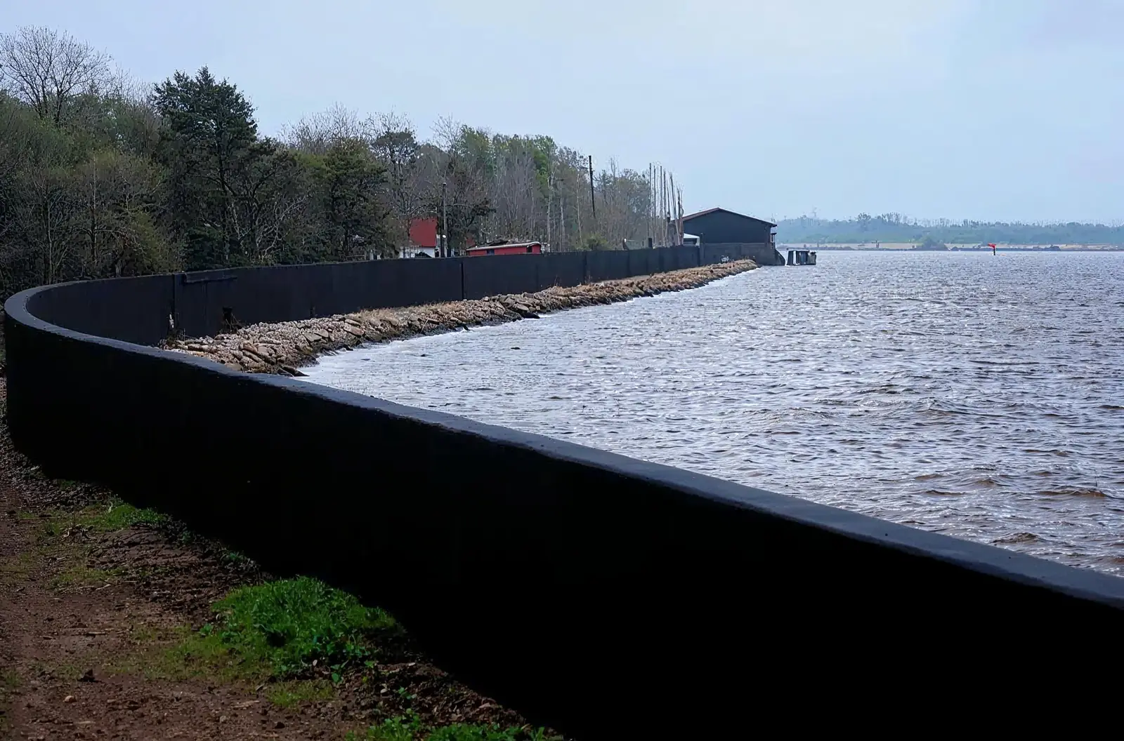 Long black coated flood wall running beside a river