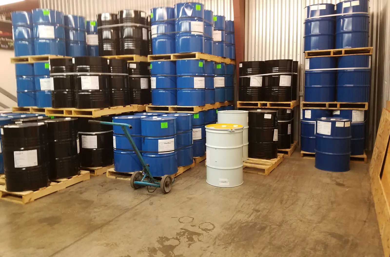 Rows of blue and black chemical drums on pallets in a warehouse