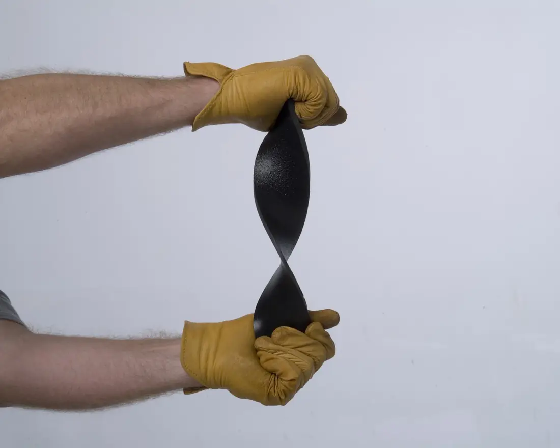 Gloved hands flexing a strip of black elastomer coating