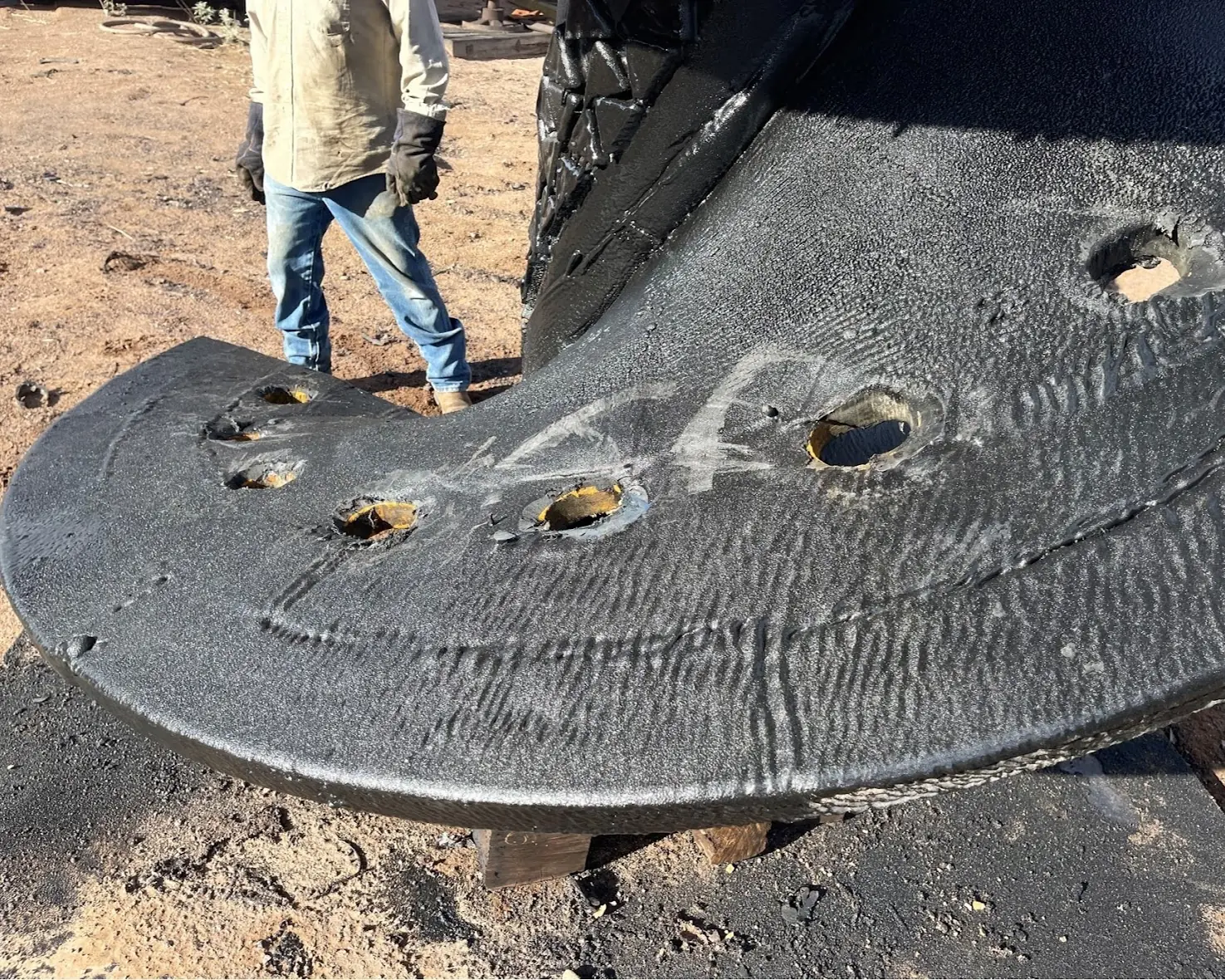 Heavy steel equipment part finished in a thick black protective coating